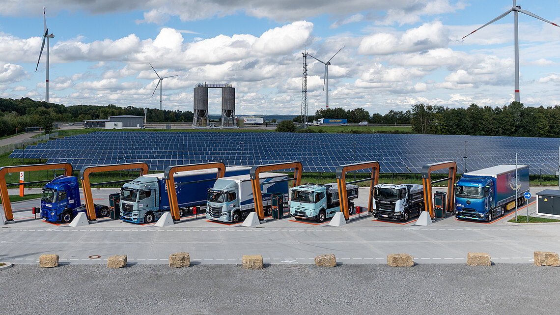 E-Lkw beim Laden im neuen Ladepark von Milence mit Solar- und Windkraft im Hintergrund – nachhaltige Mobilität im Fokus.